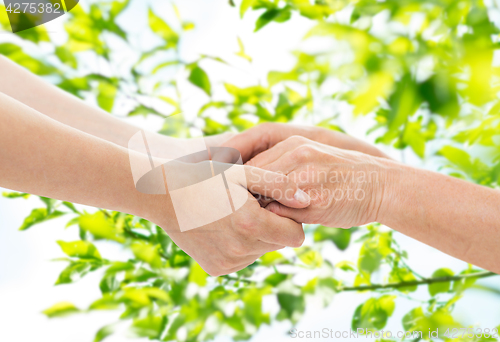 Image of close up of senior and young woman holding hands