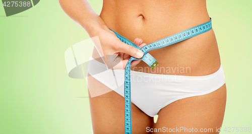 Image of close up of woman body with measure tape on waist