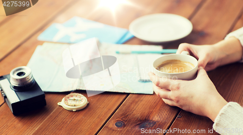 Image of close up of hands with coffee cup and travel stuff