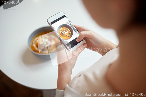 Image of woman with smartphone photographing food at cafe