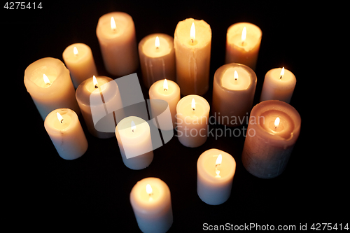 Image of candles burning in darkness over black background