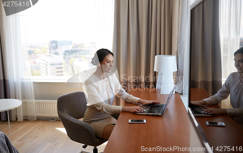 Image of businesswoman typing on laptop at hotel room