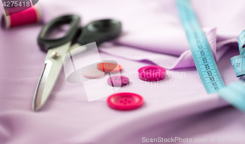 Image of scissors, sewing buttons, tape measure and cloth