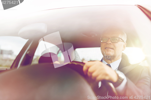 Image of happy senior businessman driving car