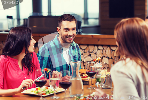 Image of happy friends having dinner at restaurant