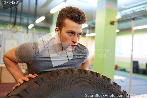 Image of man doing strongman tire flip training in gym