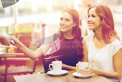 Image of women paying money to waiter for coffee at cafe