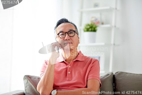 Image of happy man calling on smartphone at home