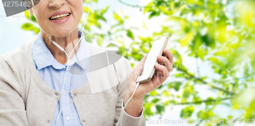 Image of happy senior woman with smartphone and earphones