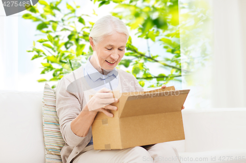 Image of happy senior woman with parcel box at home