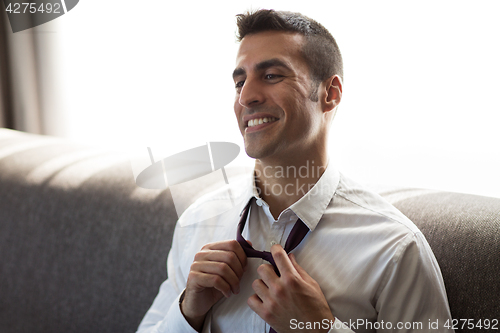 Image of happy businessman taking off his tie at hotel room