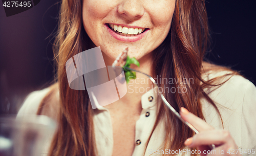 Image of happy young woman having dinner at restaurant