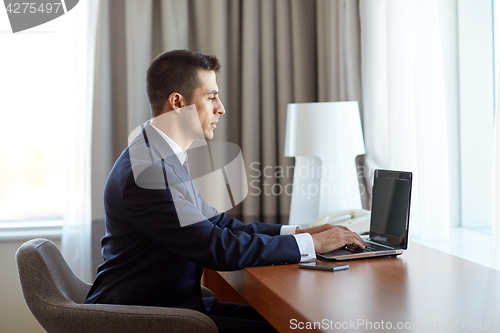 Image of businessman typing on laptop at hotel room