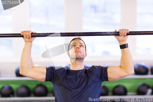 Image of man exercising on bar and doing pull-ups in gym