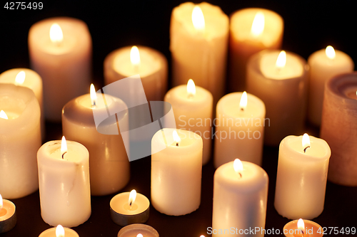 Image of candles burning in darkness over black background