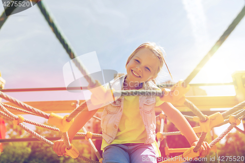 Image of happy little girl climbing on children playground