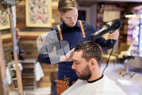 Image of barber with fan drying male hair at barbershop