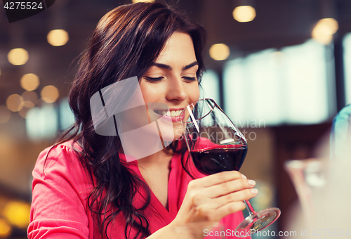 Image of smiling woman drinking red wine at restaurant