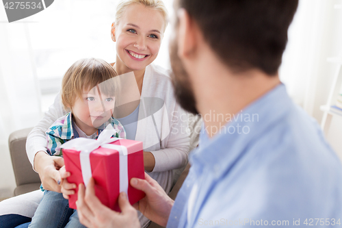 Image of happy family with birthday gift at home