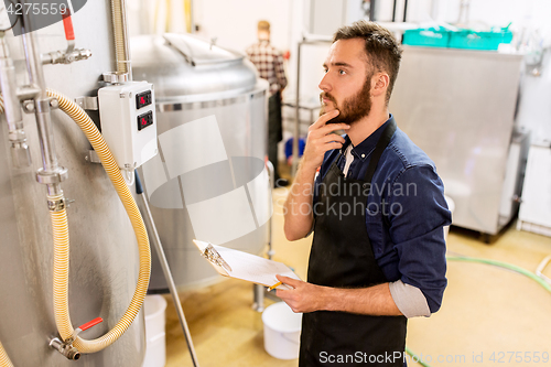 Image of man with clipboard at craft brewery or beer plant