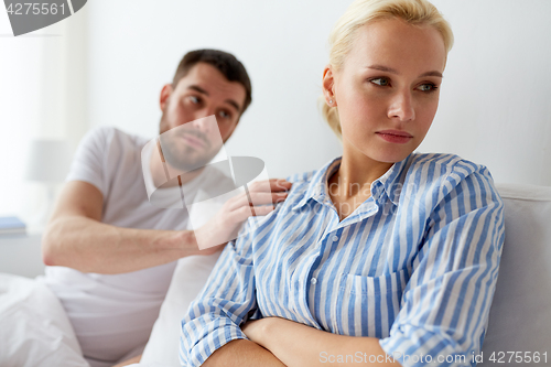 Image of unhappy couple having conflict in bed at home