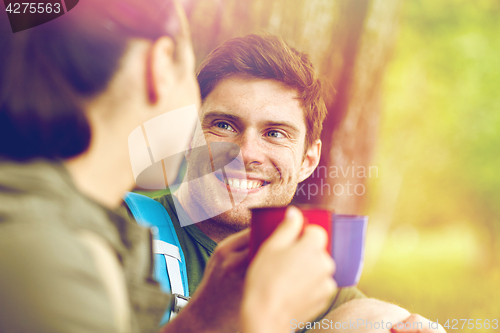 Image of happy couple with cups drinking tea in nature