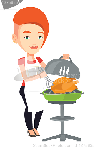 Image of Woman cooking chicken on barbecue grill.