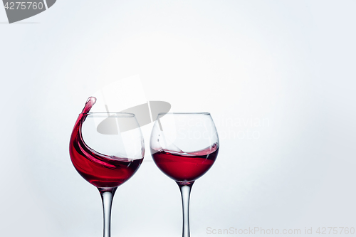 Image of Two wine glasses in toasting gesture with big splashing.
