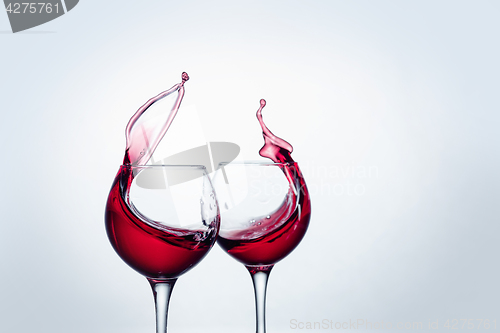 Image of Two wine glasses in toasting gesture with big splashing.