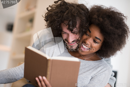 Image of multiethnic couple hugging in front of fireplace