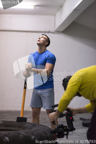 Image of man workout with hammer and tractor tire