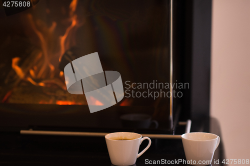 Image of two mugs in front of fireplace