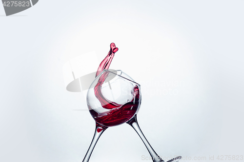 Image of Two wine glasses in toasting gesture with big splashing.