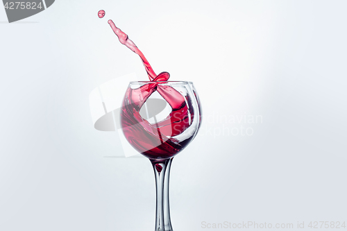 Image of Two wine glasses in toasting gesture with big splashing.