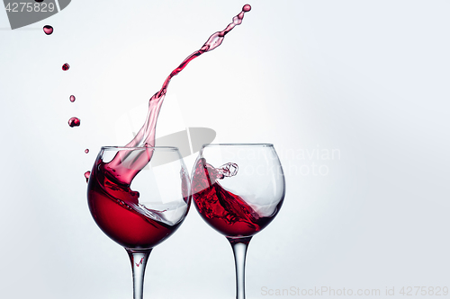 Image of Two wine glasses in toasting gesture with big splashing.