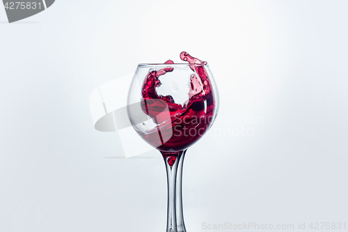 Image of Two wine glasses in toasting gesture with big splashing.