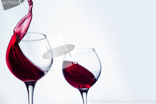 Image of Two wine glasses in toasting gesture with big splashing.