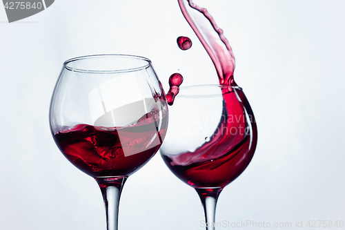 Image of Two wine glasses in toasting gesture with big splashing.