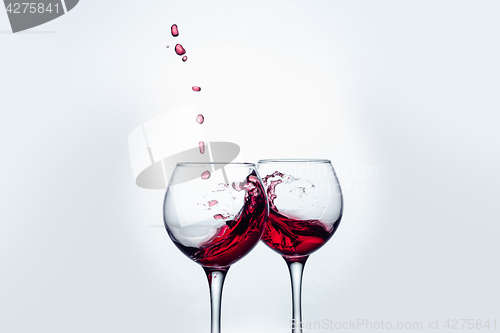 Image of Two wine glasses in toasting gesture with big splashing.