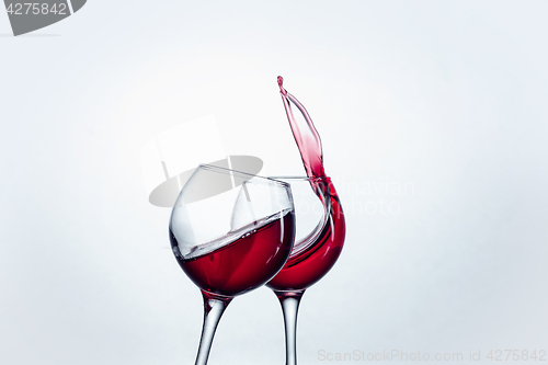 Image of Two wine glasses in toasting gesture with big splashing.