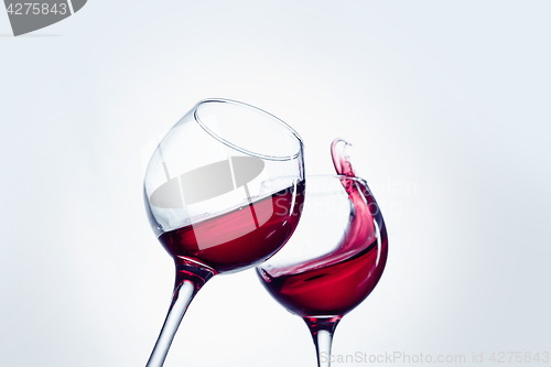 Image of Two wine glasses in toasting gesture with big splashing.