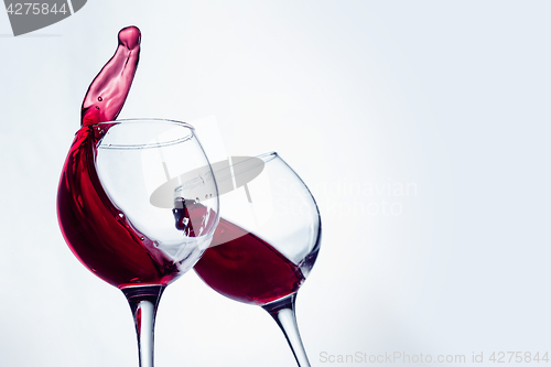 Image of Two wine glasses in toasting gesture with big splashing.