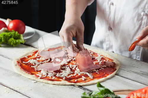 Image of Closeup hand of chef baker in white uniform making pizza at kitchen
