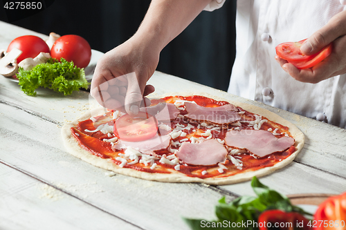 Image of Closeup hand of chef baker in white uniform making pizza at kitchen