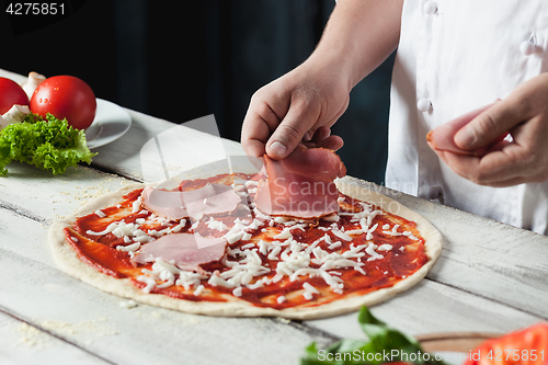 Image of Closeup hand of chef baker in white uniform making pizza at kitchen