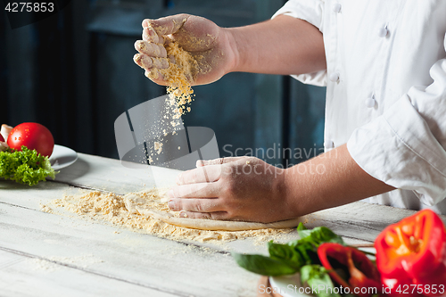 Image of Closeup hand of chef baker in white uniform making pizza at kitchen