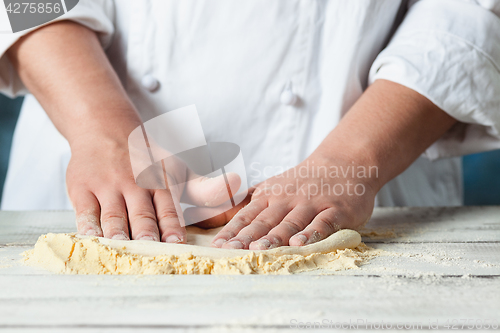 Image of Closeup hand of chef baker in white uniform making pizza at kitchen