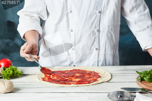 Image of Closeup hand of chef baker in white uniform making pizza at kitchen