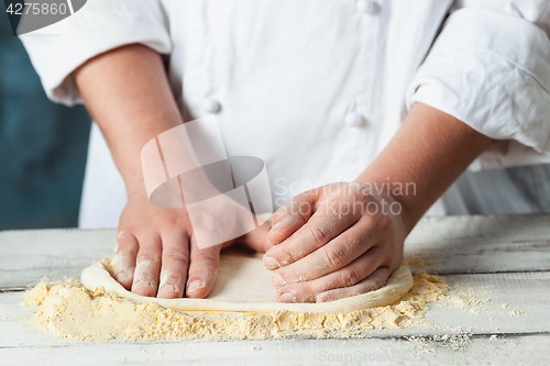 Image of Closeup hand of chef baker in white uniform making pizza at kitchen