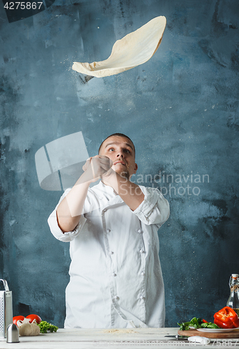 Image of Closeup hand of chef baker in white uniform making pizza at kitchen